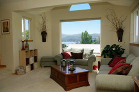 Now, the room is arranged to have the view of the lake the main focal point. Tall floral arrangements were added to walls to give height to room. The recliner was removed to make the room appear larger.